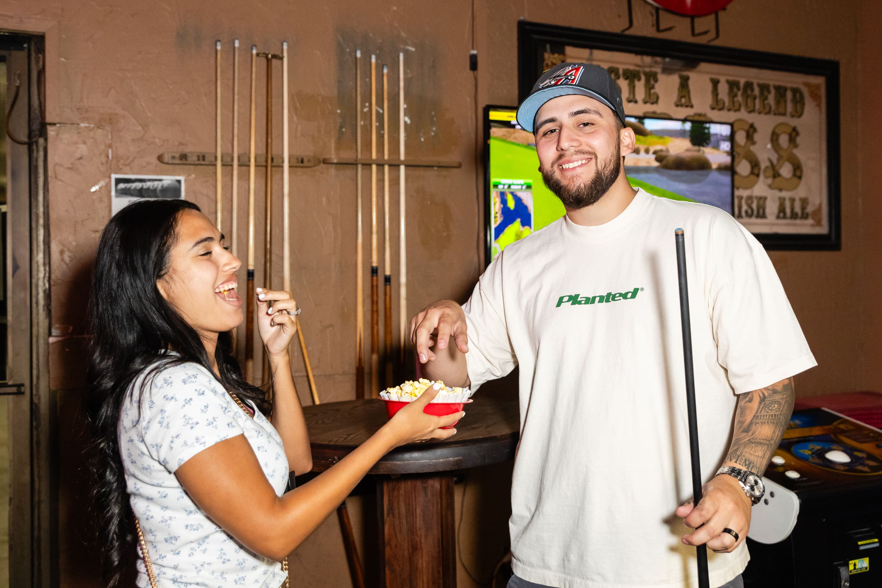 A man and woman eating food at an indoor pool.